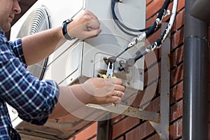 Closeup of male technician repairing outdoor air conditioner uni