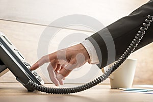 Closeup of male telemarketing operator dialing a telephone number