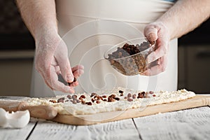 Closeup of man adds raisin into dough.
