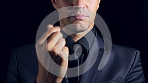 Closeup of a man in black clothes on black background. 4k. Slow motion. man rubs his fingers against each other