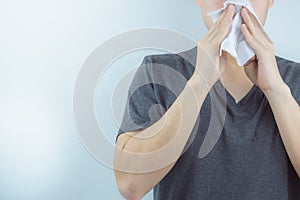 Closeup man blowing nose into tissue, man has a runny nose. Health care and medical concept