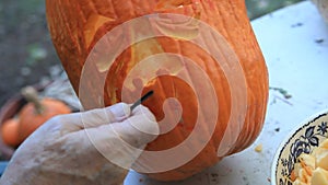 Closeup man carves Halloween pumpkin