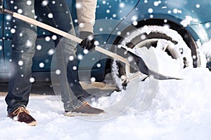 Closeup of man digging snow with shovel near car