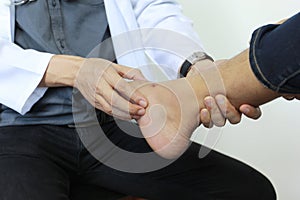 Closeup of Man feeling pain in her foot and doctor the traumatologist examines or treatment on white background, Healthy concept