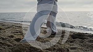 Closeup man feet stepping on sand training karate. Athlete exercising on beach.