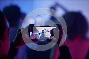 Closeup of man filming DJ at disco party via smartphone