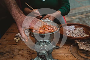 Closeup of a man grinding meat with an old-fashioned grinder on the wooden table