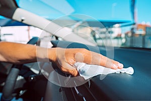 Closeup of man hand with antibacterial wet wipe or napkin cleaning car panel