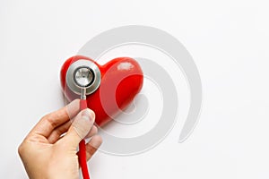 Closeup of man hand holding a red stethoscope on heart - medical diagnostic device for auscultation listening of sounds coming