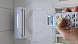 Closeup man hand holding a remote control to the air conditioning system