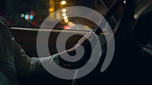 Closeup man hands driving car night road. Driver holding vehicle steering wheel