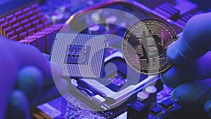 Closeup of man hands in gloves hold gold Bitcoin and cpu on motherboard background. Person shows future currency. Mining