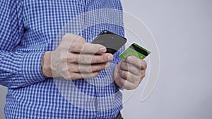 Closeup of man hands holding credit card and using smartphone.
