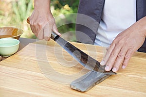 Closeup man hands sharpen knife on whetstone sharpener or grindstone.