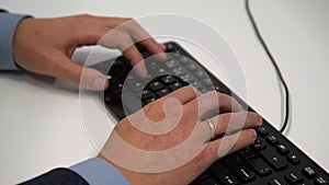 Closeup of man hands typing keyboard at the office. Business man in a suit working online with a desktop computer