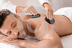 Closeup of man having hot stone massage at luxury spa