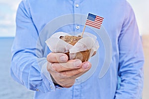 Closeup man holds cupcake with American flag of USA