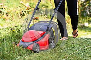 Closeup of a man with a lawn mower cutting the grass. Selective focus. Red special manual technic.