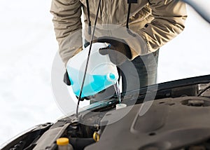 Closeup of man pouring antifreeze into water tank photo