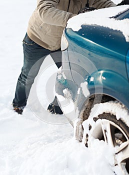 Closeup of man pushing car stuck in snow