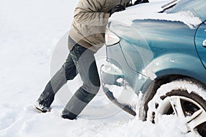 Closeup of man pushing car stuck in snow