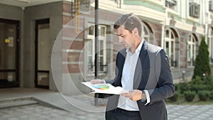 Closeup man reading documents at street. Man going to work in suit at street