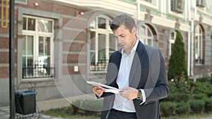 Closeup man reading documents at street. Man going to work in suit at street