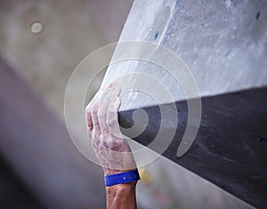 Closeup of man's hand on handhold on artificial climbing wall