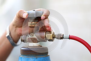 Closeup man`s hand operating valve of gas cylinder