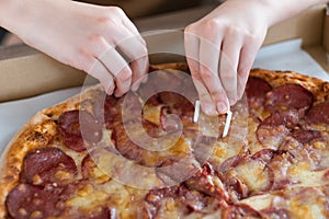 Closeup of a man& x27;s hand taking a slice of pepperoni pizza. Pizza with salami and cheese