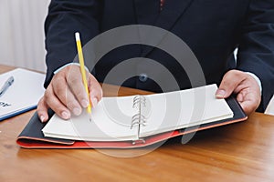 Closeup of man`s hand write on notebook. Holding and writing with a pencil