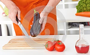 Closeup man`s hands cutting vegetables on a work surface in a kitchen. Dieting concept.