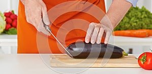 Closeup man`s hands cutting vegetables on a work surface in a kitchen.