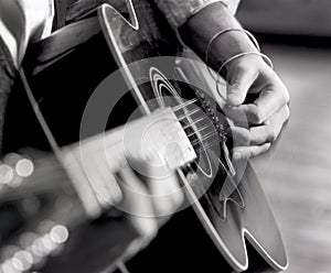 Closeup man`s hands, fingers, strumming acoustic guitar with pick