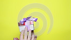 closeup on man's hands holding gift with red ribbon.