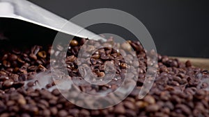 Closeup man scooping roasted coffee grains using shovel. Vapor coming over seeds