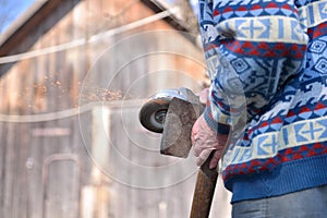 Closeup of man sharpen an ax using electric grinder. Sparks w