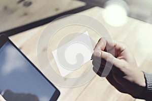 Closeup Man Showing Blank White Business Card, Holding Hand Modern Digital Tablet.Wood table Blurred Background.Mockup