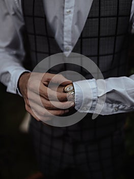 Closeup of a man in a Suiting Fabric with a white shirt holding his yellow fancy watch