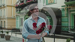 Closeup man throwing red roses at paved street. Man smelling roses at street