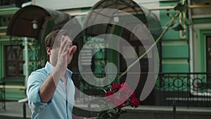 Closeup man throwing red roses at paved street. Man smelling roses at street