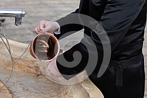 Closeup of a Jewish man using a copper cup for a ritual hand washing prior to prayer. photo