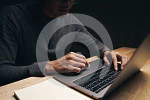 Closeup of a man using a laptop computer on the wooden table, searching, browsing, social media, message, email, internet digital