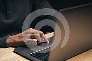 Closeup of a man using a laptop computer on the wooden table, searching, browsing, social media, message, email, internet digital