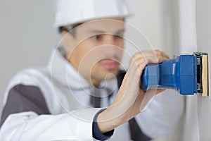 closeup man using sander on wall
