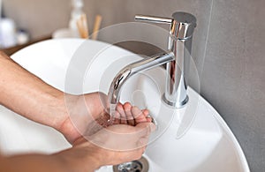 Closeup of man washing his hands at bathroom