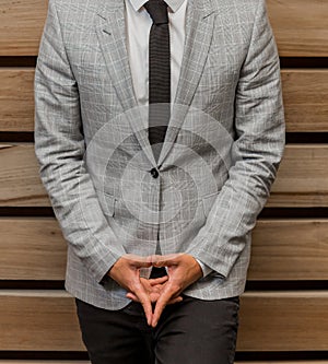 Closeup of a man wearing a light gray suit with a light shirt and black tie - business style