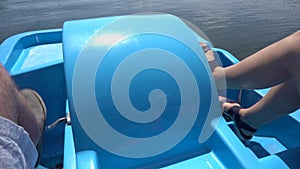 Closeup of man and woman legs pedaling water cycle catamaran boat pedals