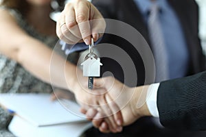 Closeup of man and woman shaking hands over keys to apartment in hands of insurance agent