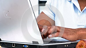 Closeup of a man working on the laptop while having breakfast